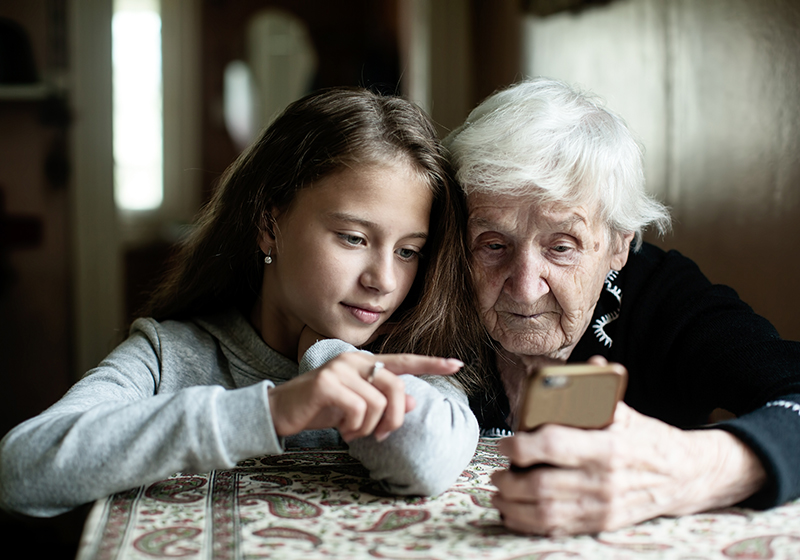 Child helping her grandmother with her mobile phone.