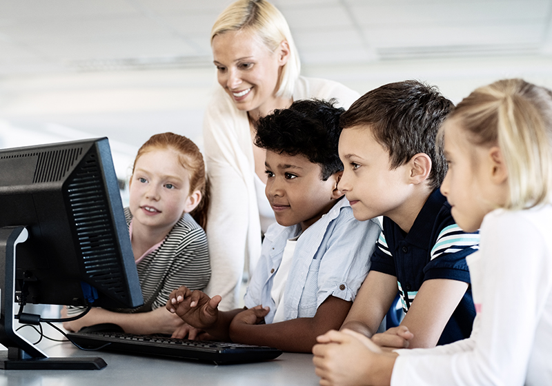 Children and a techer looking at something on the screen. IST information security policy.